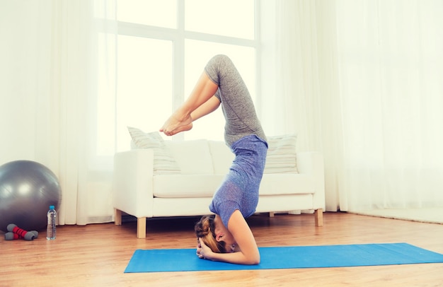 fitness, deporte, gente y concepto de estilo de vida saludable - mujer haciendo yoga en pose de pie en la alfombra