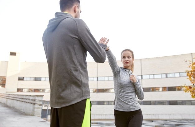 fitness, deporte, gente, ejercicio y concepto de artes marciales - mujer joven con entrenador trabajando en huelga de autodefensa en la calle de la ciudad