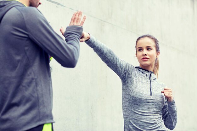 Foto fitness, desporto, artes marciais, autodefesa e conceito de pessoas - mulher com treinador pessoal a exercitar-se ao ar livre