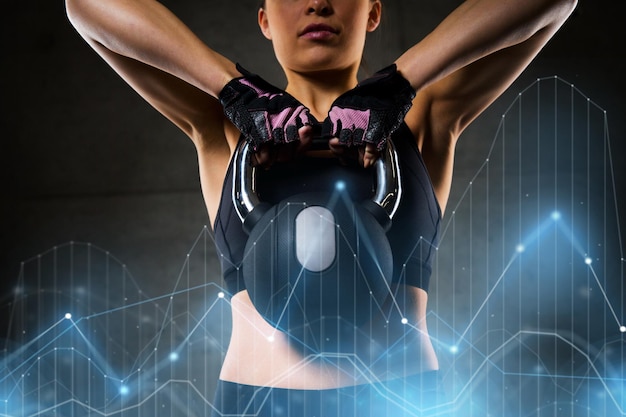 Foto fitness, desporto, exercício, levantamento de pesos e conceito de pessoas - jovem a flexionar os músculos com kettlebell no ginásio
