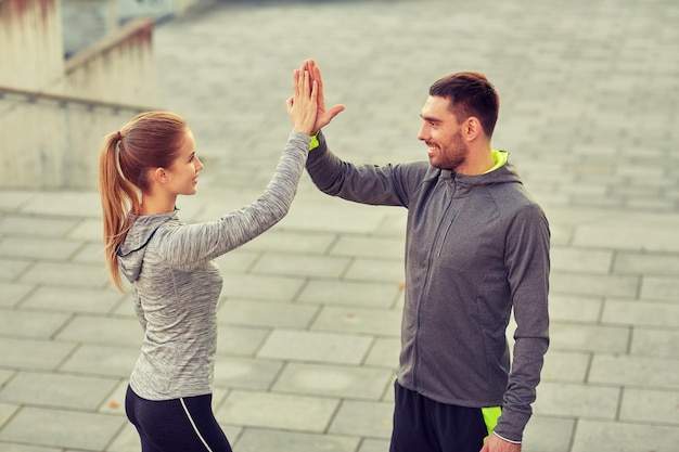 fitness, desporto, gesto, pessoas e conceito de sucesso - casal feliz dando cinco no ar livre