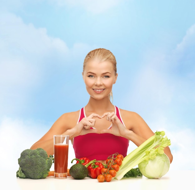 fitness, dieta e conceito de comida - mulher sorridente com alimentos orgânicos, mostrando a forma do coração com as mãos