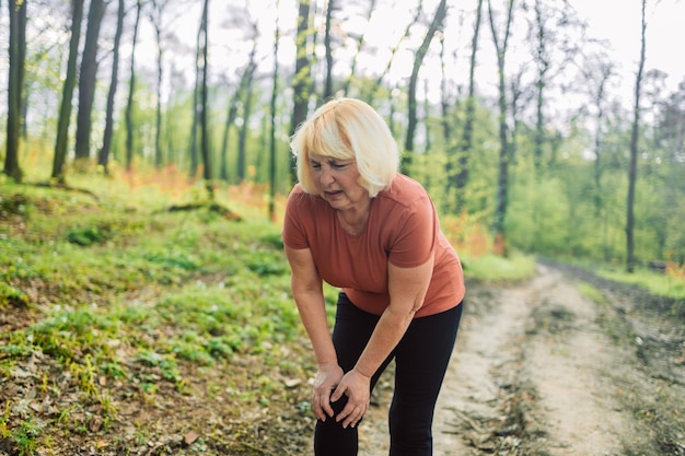 Fitness dolor de rodilla y ss mujer en el parque después de hacer ejercicio y entrenamiento de maratón para una vida saludable