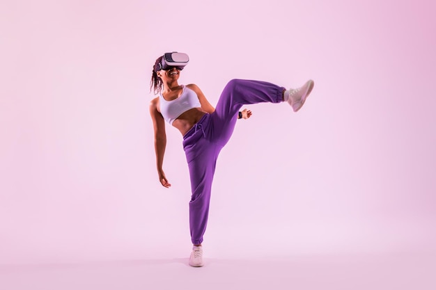Fitness en la era digital Mujer negra haciendo ejercicio en el metaverso con auriculares de realidad virtual con fondo de neón rosa