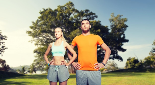 fitness, esporte, amizade e conceito de estilo de vida saudável - casal feliz se exercitando sobre o fundo do parque de verão