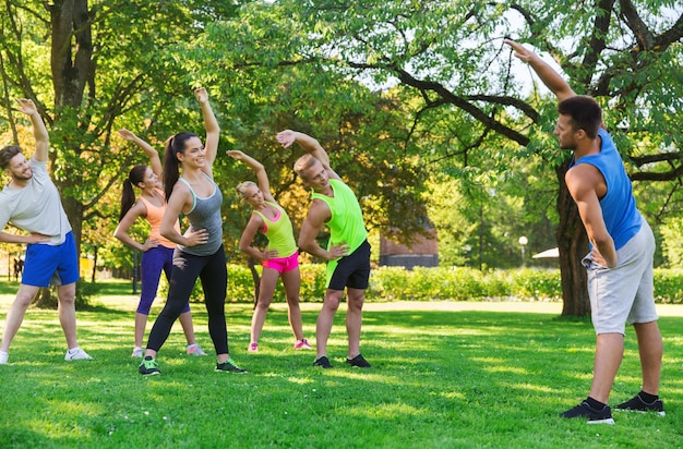 fitness, esporte, amizade e conceito de estilo de vida saudável - grupo de amigos adolescentes felizes ou desportistas exercitando e esticando as mãos no campo de treinamento