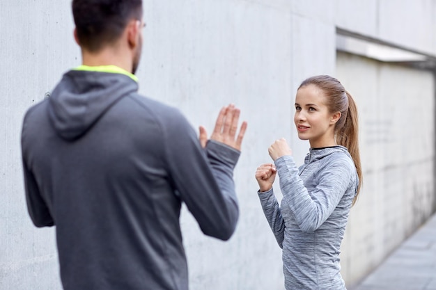 Foto fitness, esporte, artes marciais, autodefesa e conceito de pessoas - mulher feliz com personal trainer malhando greve ao ar livre