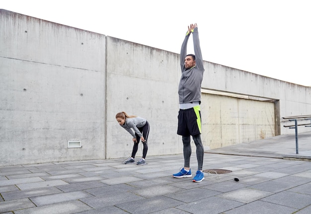 fitness, esporte, exercício, treinamento e conceito de pessoas - casal cansado se alongando após o exercício ao ar livre na rua da cidade