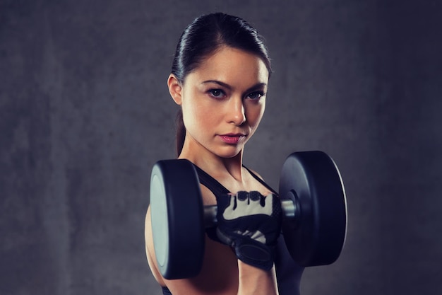 fitness, esporte, exercício, treinamento e conceito de pessoas - jovem flexionando músculos com halteres no ginásio