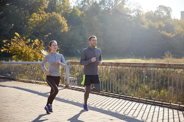 fitness, esporte, pessoas e conceito de corrida - casal feliz correndo ao ar livre