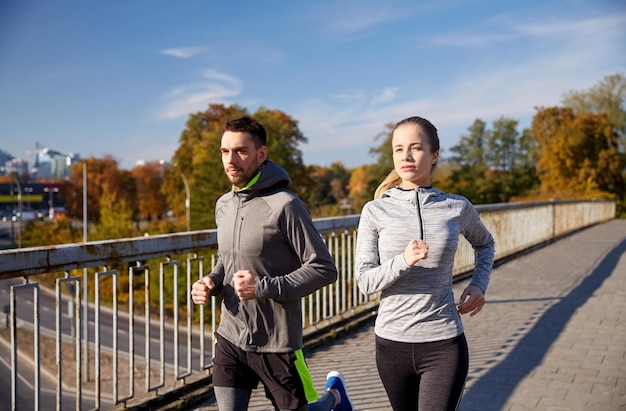 fitness, esporte, pessoas e conceito de corrida - casal feliz correndo ao ar livre