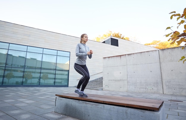 fitness, esporte, pessoas e conceito de estilo de vida saudável - mulher exercitando no banco ao ar livre