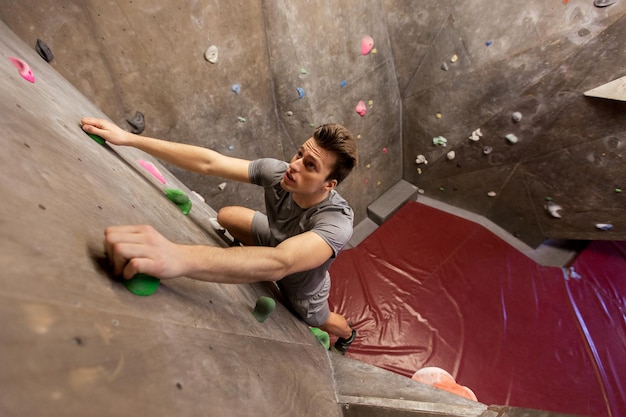 fitness, esporte radical, bouldering, pessoas e conceito de estilo de vida saudável - jovem se exercitando na academia de escalada indoor