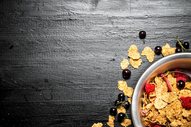 Fitness Essen. Müsli mit einer Vielzahl von Waldbeeren. Auf einem schwarzen Holztisch.