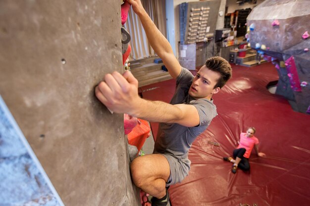 Fitness, Extremsport, Bouldering, Menschen und gesundes Lebensstilkonzept - Mann und Frau trainieren im Indoor-Kletterstudio