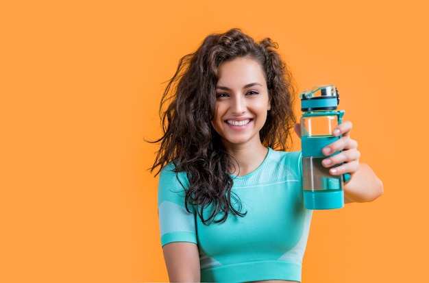 Fitness-Frau mit Sportwasserflasche Kopierraum Fitness-Frauen halten Sport-Wasserflasche isoliert auf gelbem Hintergrund Fitness und Sport