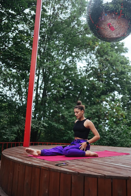 Fitness-Frau sitzt auf der Matte und macht Yoga