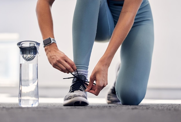 Fitness-Frau und Schuh für Laufvorbereitungstraining oder Trainingsübung mit Wasserflasche im Freien Weibliche Bindeschnürsenkel, die sich auf Sportübungen oder gesundes Cardio im Freien vorbereiten