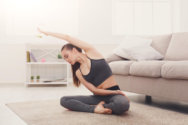 Fitness Frau Warmup Stretching in Yoga-Pose zu Hause. Junges schlankes Mädchen macht Yogaübungen, Kopierraum