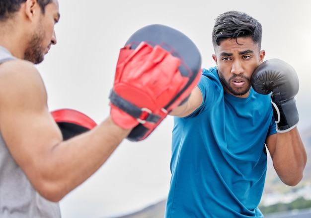 Fitness en el gimnasio y boxeo masculino con entrenamiento de entrenadores y motivación para el entrenamiento de la salud y la autodefensa Ejercicio de entrenamiento y compromiso de bienestar fuerte atleta boxeador al aire libre en una ciudad urbana o Brasil