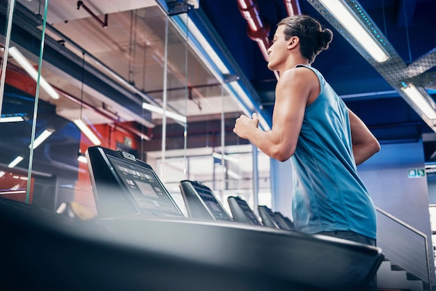 Fitness en el gimnasio y hombre corriendo en la cinta de correr para el bienestar de la salud y el ejercicio cardiovascular solo y potencia. Entrenamiento de Runner y chico en el centro deportivo para entrenar la energía y la velocidad y el rendimiento de la resistencia.