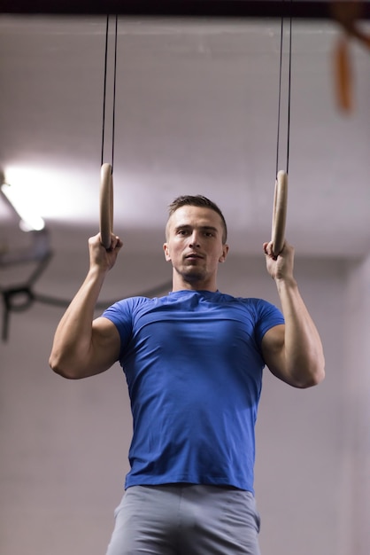 Foto fitness gutaussehender mann, der tauchübungen mit ringen im fitnessstudio macht