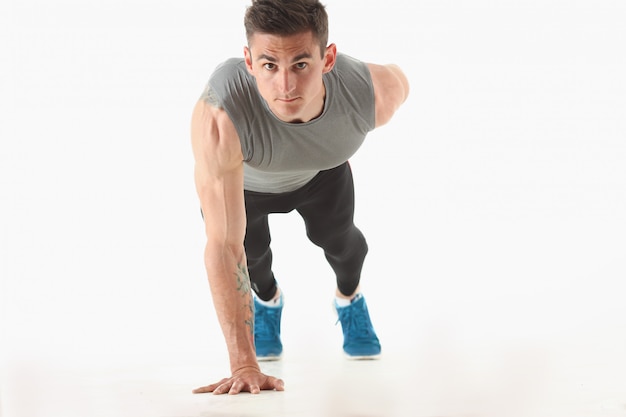 Fitness hombre retorciéndose del piso demuestra buenos ejercicios físicos aislados