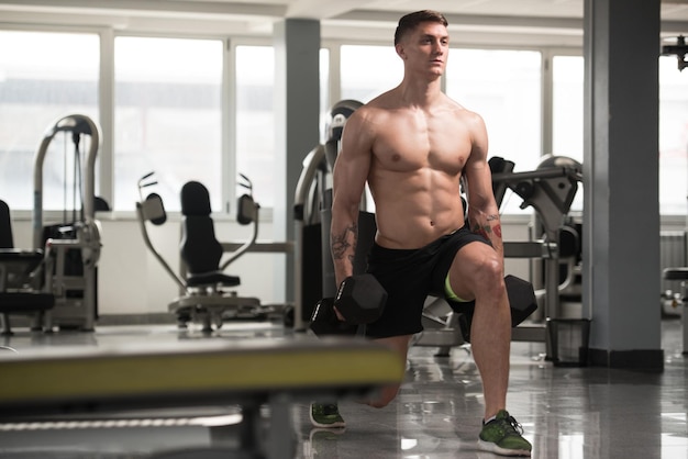 Fitness hombre usando pesas ejercitar las piernas dentro del gimnasio