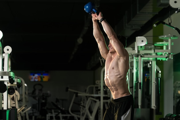 Fitness hombre usando pesas rusas dentro del gimnasio