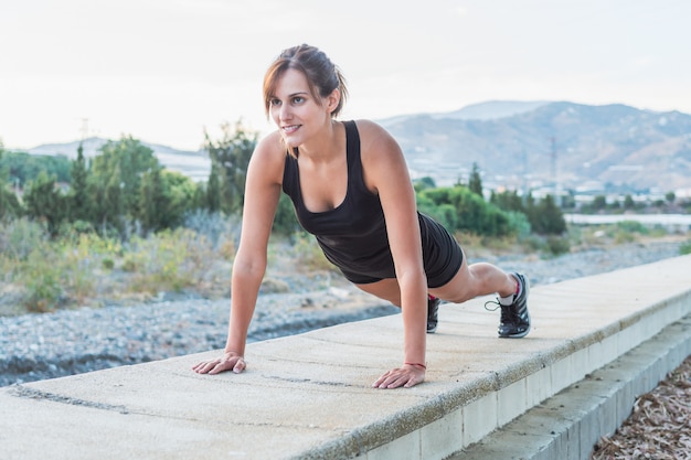 Fitness Jovem mulher fazendo push ups treino no parque