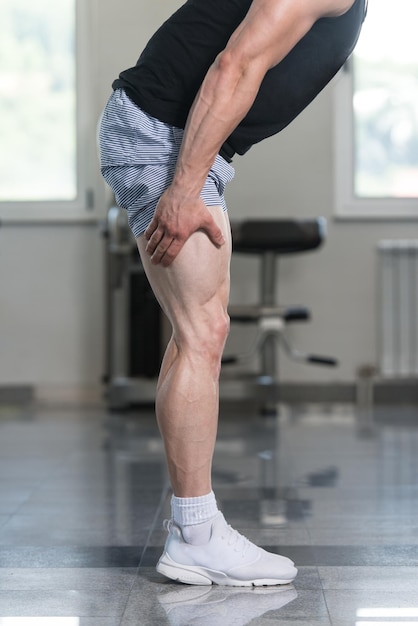 Fitness joven hombre se extiende en el gimnasio