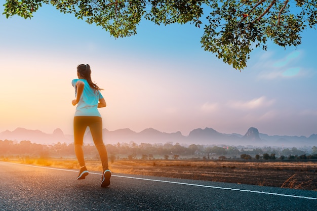 Fitness joven mujer asiática está corriendo y haciendo jogging al aire libre en la carretera por la mañana para la salud del estilo de vida.