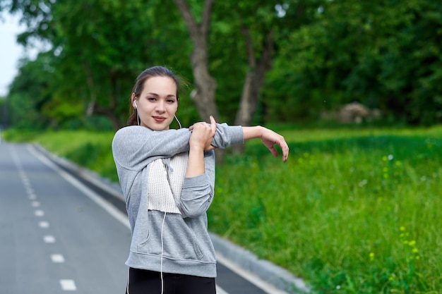 Fitness joven mujer asiática estirando las manos después de correr al aire libre después de correr
