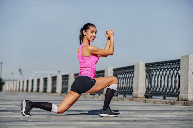 Fitness junge Frau, die Beine nach dem Laufen streckt. Outdoor-Sportporträt