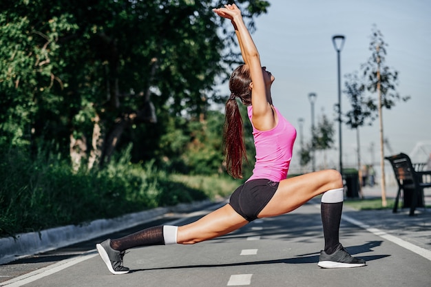 Fitness junge Frau, die Beine nach dem Laufen streckt. Outdoor-Sportporträt