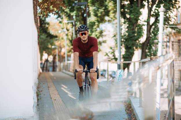 Fitness junger Mann mit Schutzhelm und Sportbrille beim Radfahren im Freien Kaukasische männliche Person mit schwarzem Fahrrad für das Training auf den Straßen der Stadt