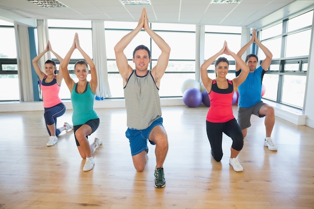 Foto fitness-klasse und lehrer knien in namaste position