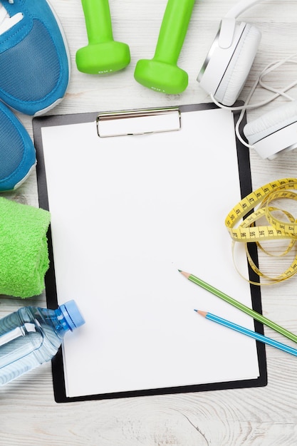 Foto fitness-konzept-hintergrund mit turnschuhen, kopfhörern, hanteln, wasserflasche und handtuch. draufsicht mit platz für ihren text