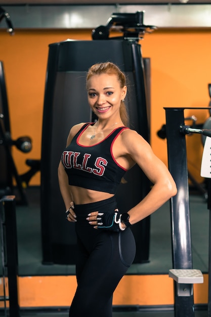 Fitness-Mädchen mit einem schönen Lächeln posiert im Fitnessstudio