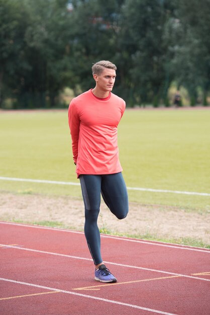 Fitness Man estirando antes del entrenamiento corriendo en la pista