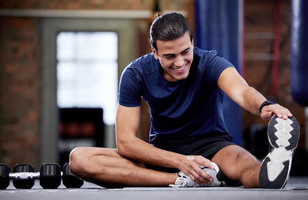 Fitness man y estirar las piernas en el gimnasio para la movilidad y la flexibilidad de la salud Bienestar deportivo y calentamiento masculino feliz o preparación para el ejercicio de entrenamiento o entrenamiento en el gimnasio para un cuerpo sano