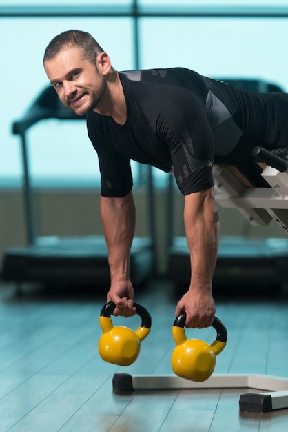 Foto fitness-mann arbeitet mit kettlebell in einer kettlebell-übung im fitnessstudio