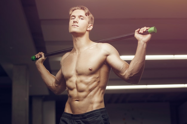 Fitness-Mann beim Training im Fitnessstudio mit Bodybar-Streckmuskeln