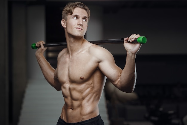 Fitness-Mann beim Training im Fitnessstudio mit Körperstangen, die Muskeln dehnen.