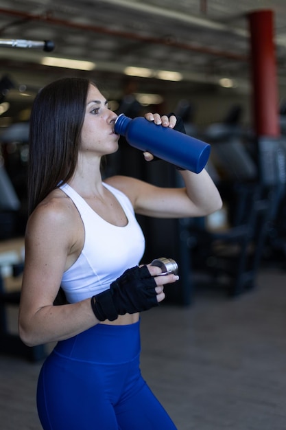 Fitness mujer bebiendo agua para hidratarse después del entrenamiento