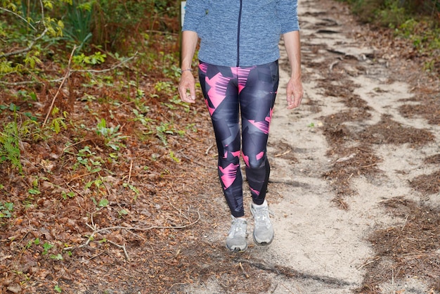 Fitness mujer cara piernas delgadas fit runner trotando por un sendero al aire libre en el parque de la ciudad