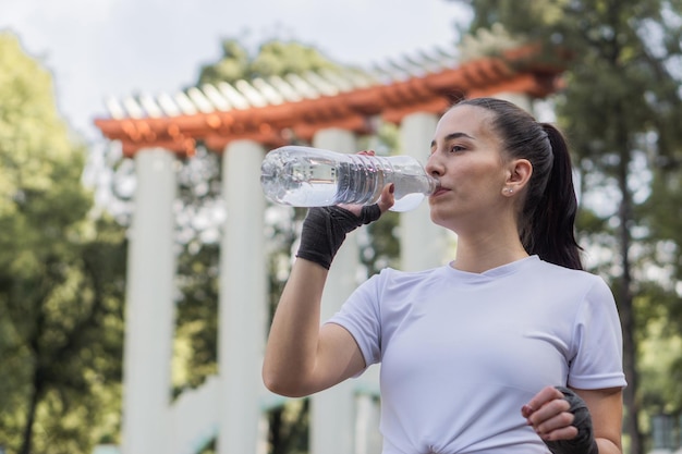 Fitness mujer caucásica bebiendo agua de una botella en un parque en la Ciudad de México.