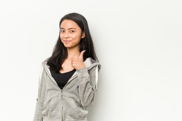 Fitness mujer china joven sonriendo y levantando el pulgar hacia arriba