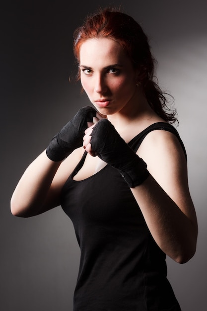 Fitness mujer ejercicio estirar brazos boxeo peso golpe en fondo oscuro estudio iluminación degradado gris luz superior sombra baja exposición copia espacio concepto Mujer puede hacer deporte 6 paquetes