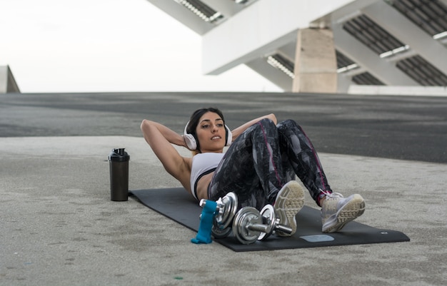 Foto fitness mujer entrenando al aire libre y haciendo ejercicios abdominales